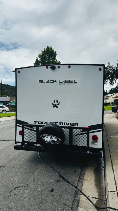 Rear view of a white Forest River Black Label Cherokee RV rental, showcasing a spare tire with a wolf logo and paw print.. Forest River Cherokee Grey Wolf 2027