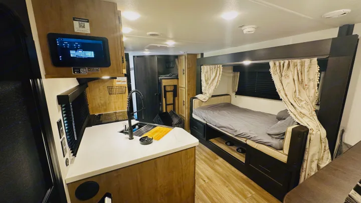 Inside a modern RV rental: kitchen sink, digital control panel, and sleeping area with bunk beds.. Forest River Cherokee Grey Wolf 2027