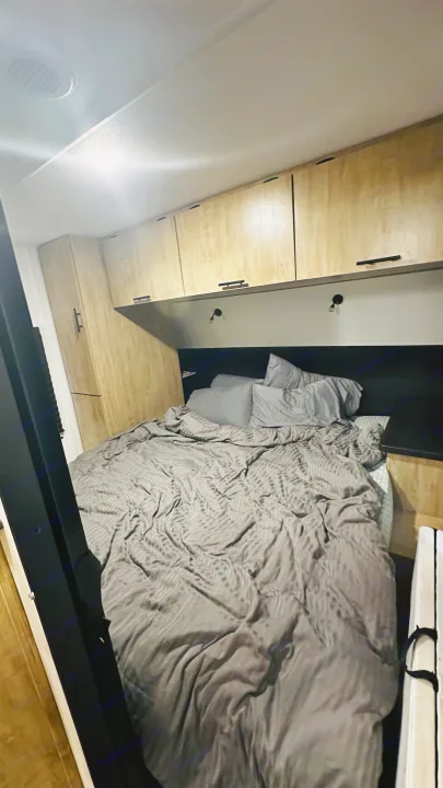 Cozy RV rental bedroom with light wood cabinets, grey bed, and reading lights, perfect for your next trip.. Forest River Cherokee Grey Wolf 2027