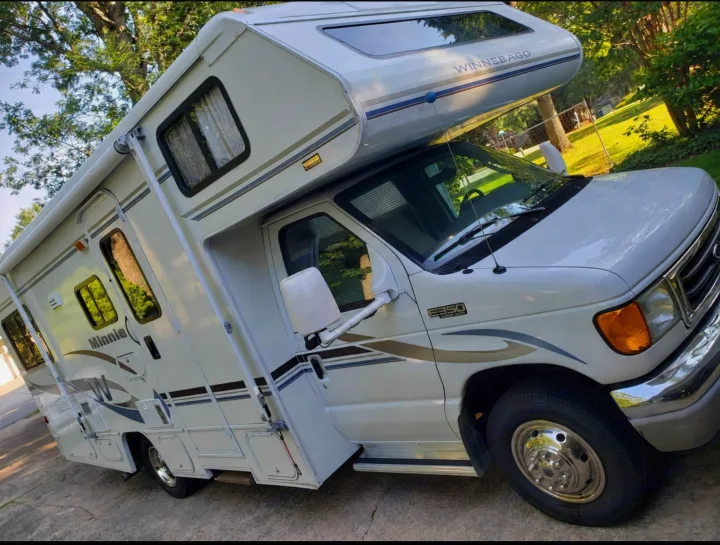 This white Winnebago Minnie Class C motorhome is ideal for an rv rental. Parked outdoors on a sunny day.. Winnebago Minnie Winnie 2004