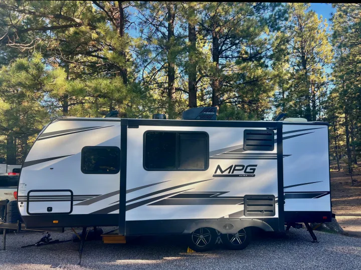 White MPG Ultra-Lite rv rental parked at a serene campsite with tall pine trees. Perfect for your next outdoor adventure.. Cruiser RV MPG Ultra Lite 2022
