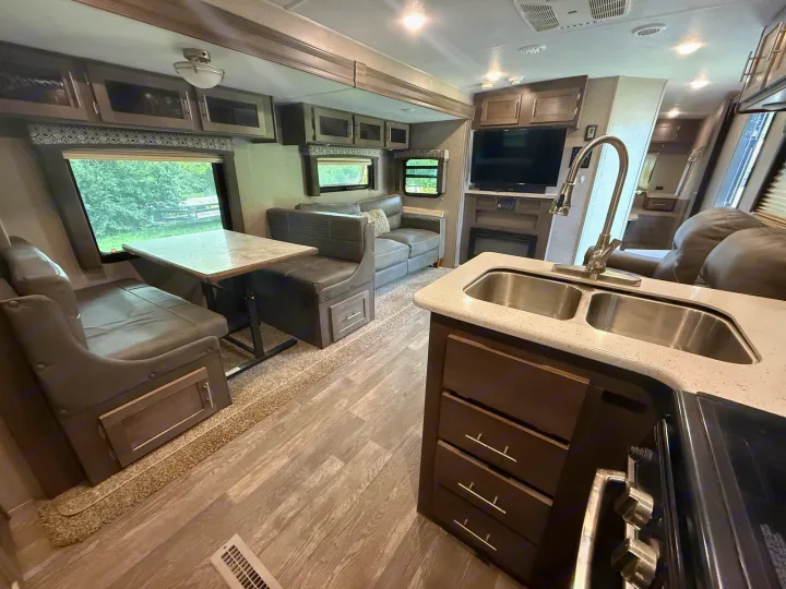 Spacious RV rental interior featuring a modern kitchen, dining booth, and comfortable living area with a TV.. Forest River Flagstaff Super Lite 2018