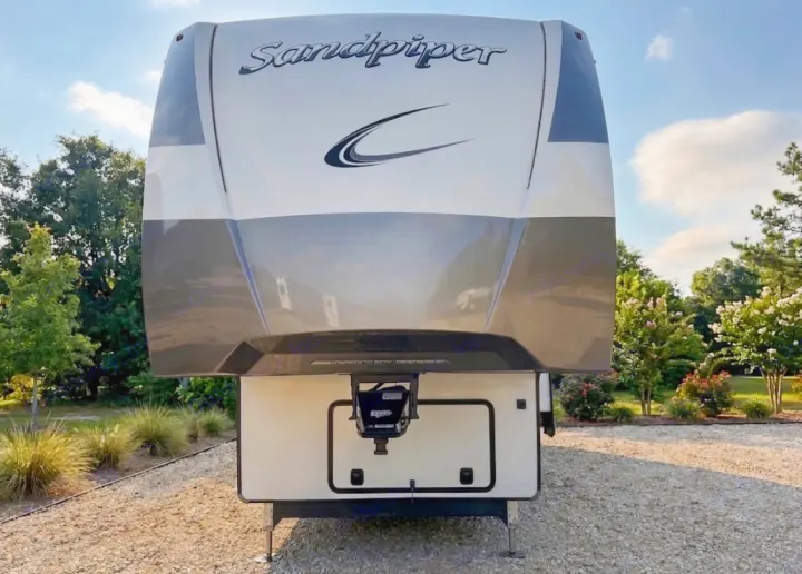 Front view of a Sandpiper fifth-wheel RV rental, parked on gravel. Ready for your next camping or travel adventure!. Forest River Sandpiper 2022
