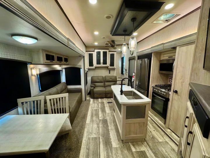 Modern RV rental interior: well-appointed kitchen island, stainless appliances, dining area, & cozy living space for comfortable travels.. Forest River Sandpiper 2022
