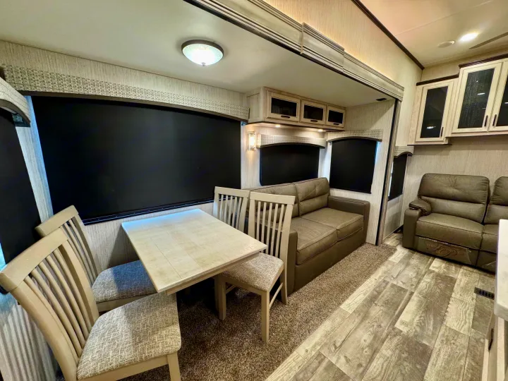 Modern rv rental interior with dining table, plush sofa, and comfortable living space. Ideal for your next adventure.. Forest River Sandpiper 2022