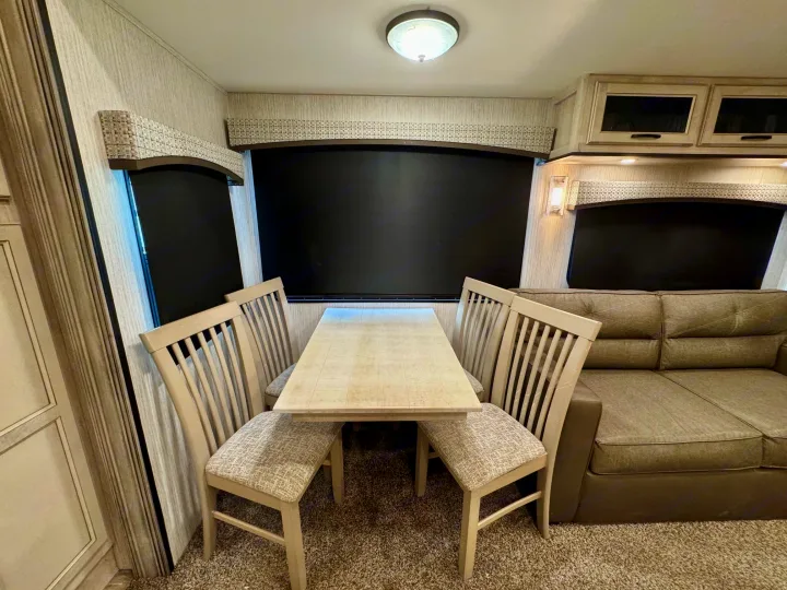 Comfortable RV rental interior with a dinette, four chairs, a sofa, and overhead storage, perfect for your next trip.. Forest River Sandpiper 2022
