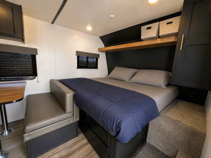 Modern RV rental interior with a cozy bed, built-in bench seating, and storage. Ideal for your next camper adventure.. Keystone RV Springdale 2022