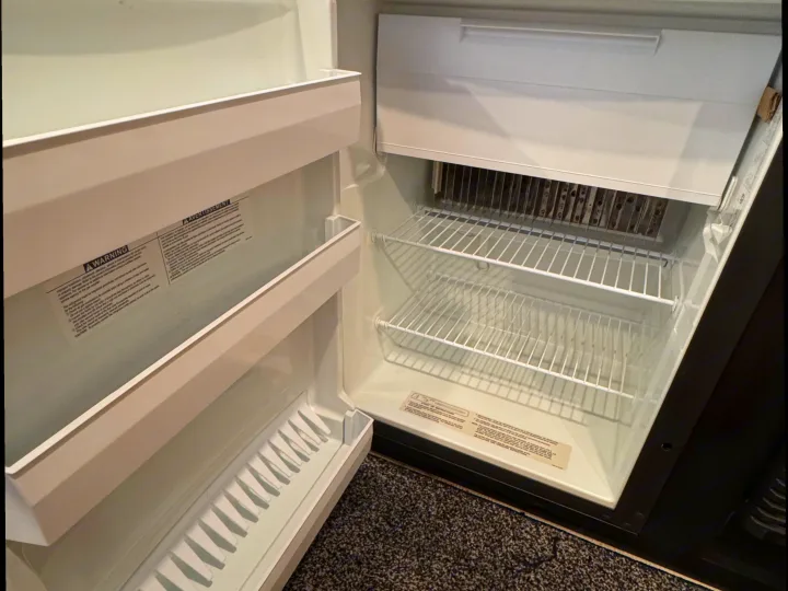 Empty, clean RV rental refrigerator, with wire shelves and a small freezer compartment. Ready for your trip!. Keystone RV Springdale 2022