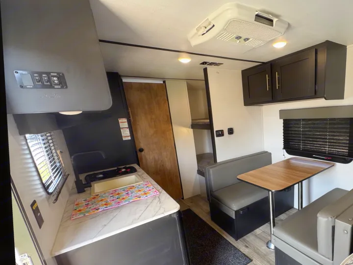 Explore this modern rv rental interior with a cozy kitchenette, dinette, bunk beds, and AC. Ideal for family adventures.. Keystone RV Springdale 2022