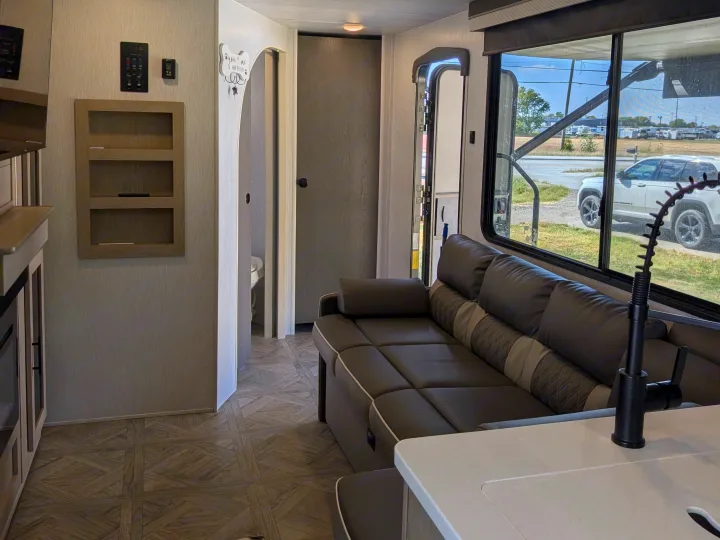 Inside a modern RV rental: comfortable living space with sofa, kitchen faucet, and exterior view. Great for travel!. Forest River Salem Cruise Lite Platinum 2024