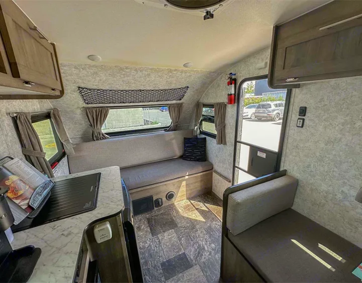 Cozy RV rental interior featuring a compact kitchen, comfortable bench seating, and bright windows for your adventures.. Prolite Lounge 2022