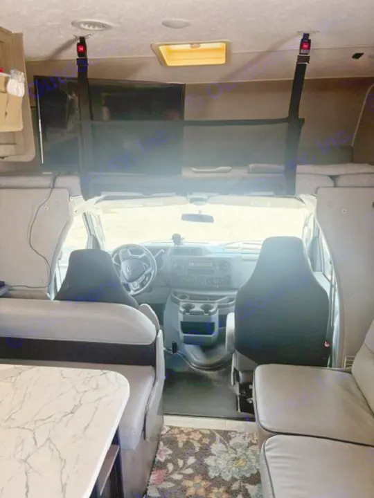 RV rental interior view towards the cab. Features front seats, overhead bunk, and entertainment for a comfortable motorhome trip.. Coachmen Freelander Freelander 2022
