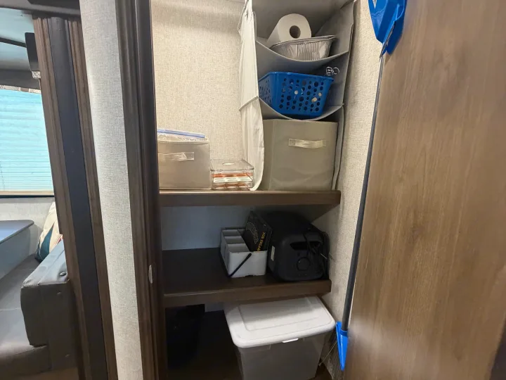 RV rental's organized closet: Multi-shelf unit with hanging storage, bins, and travel supplies for efficient interior living.. Keystone RV Cougar 2019