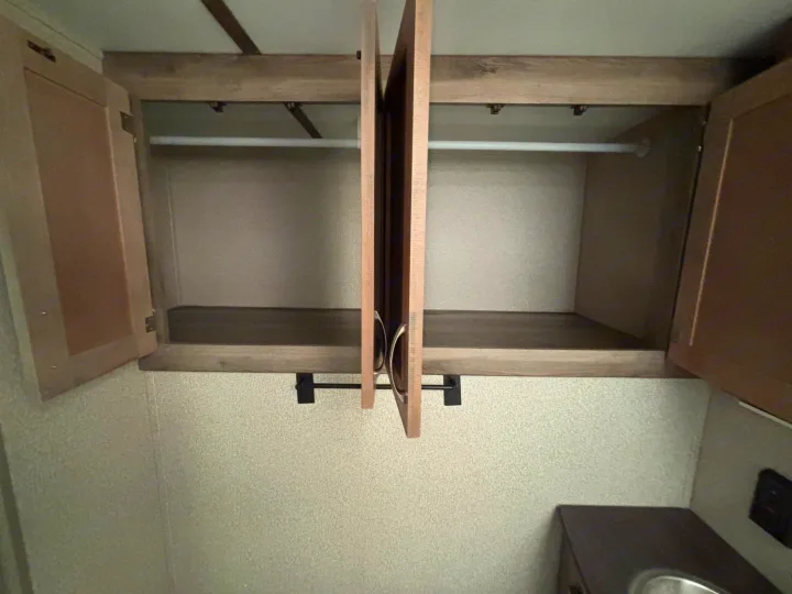 This rv rental features an open overhead wardrobe, showing a hanging rod and shelf for convenient storage.. Keystone RV Sprinter Campfire Edition 2018