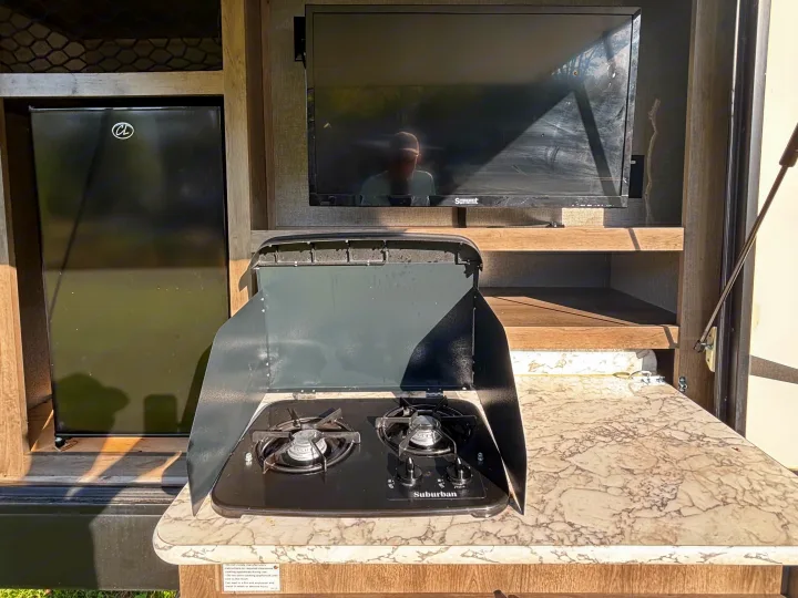This RV rental features an outdoor kitchen with a Suburban gas stove, mini-fridge, and a Summit TV, for convenient outdoor living.. Keystone RV Sprinter Campfire Edition 2018