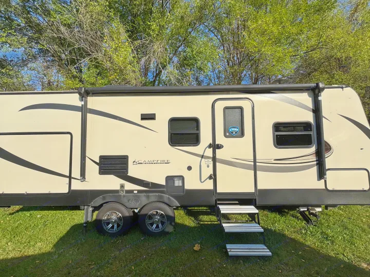 A clean beige travel trailer, branded 'Campfire Edition', with a retractable awning and steps, perfect for rv rental vacations.. Keystone RV Sprinter Campfire Edition 2018