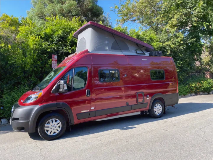This red Winnebago Solis pop-top RV rental is parked on a sunny street, ready for your next adventure.. Winnebago Solis 2024