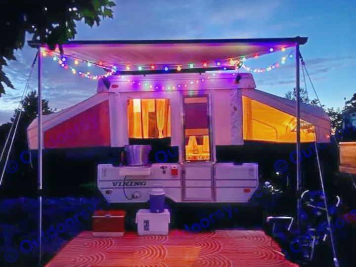 Inviting pop-up RV rental at night, adorned with colorful string lights under the awning, showcasing a cozy interior.. Viking Recreational Vehicles, INC. Model 548 2000