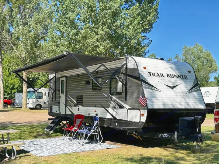 A Trail Runner RV rental is set up at Silver Lake Resort, featuring an extended awning, chairs, and a picnic table.. Heartland RVs Trail Runner 2021