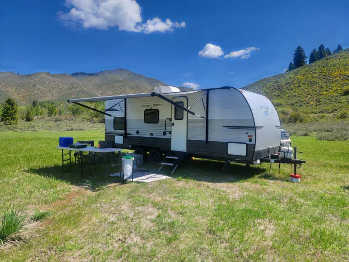Enjoy your rv rental getaway! An Avenger LT travel trailer is set up for camping in a beautiful mountain meadow.. Forest River Avenger 2020