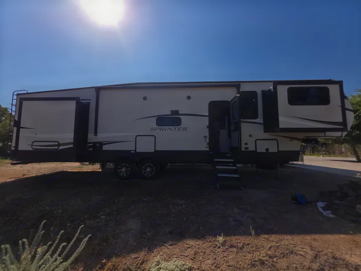 Spacious Sprinter fifth-wheel RV rental parked at a sunny campsite with extended slide-outs, ready for outdoor adventure.. Keystone RV Sprinter Limited 2021