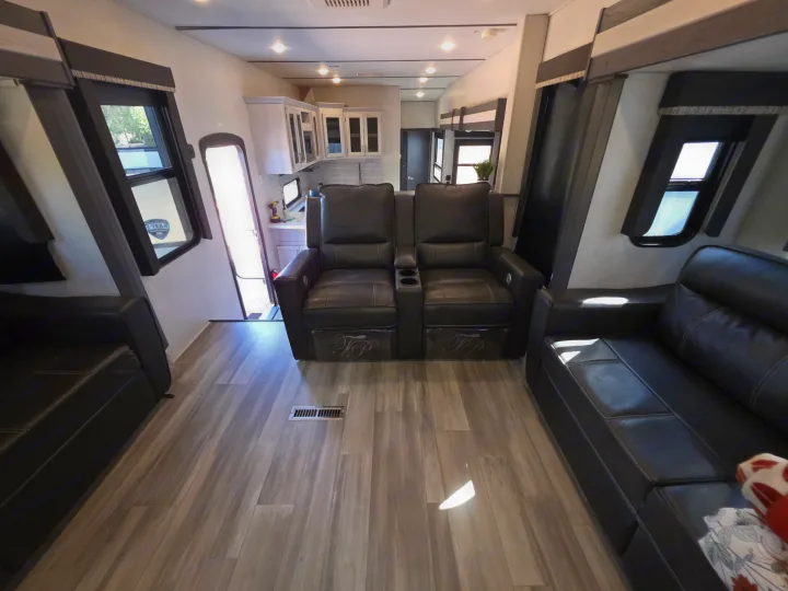 This RV rental's modern interior features a comfortable living area with black leather recliners, sofas, and a full kitchen view.. Keystone RV Sprinter Limited 2021