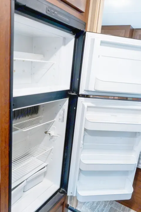 Empty, clean RV rental refrigerator and freezer, featuring shelves and door storage, prepped for your adventure.. Forest River Forester 2020
