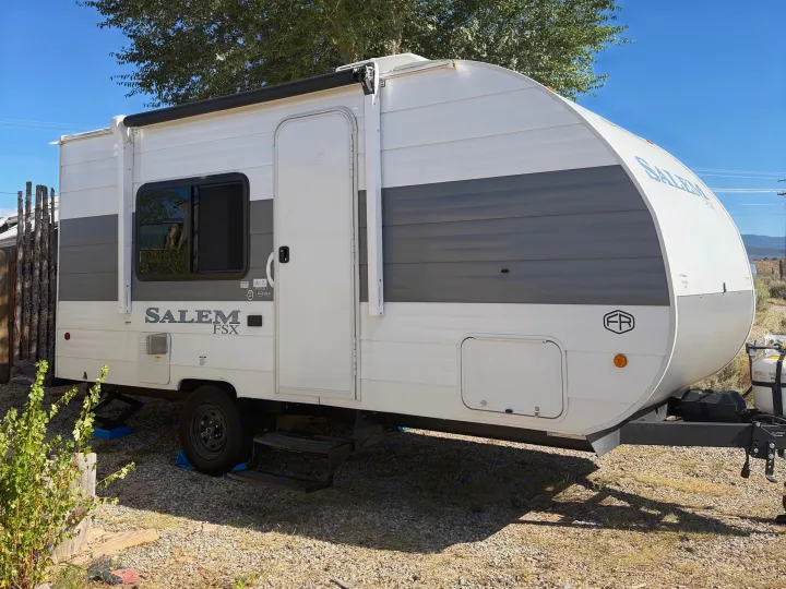 White and gray Salem FSX travel trailer RV rental parked on gravel, ready for adventures under a clear blue sky.. Forest River Salem FSX 2026