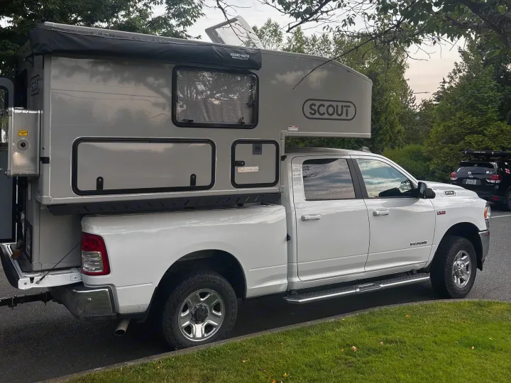White Ram pickup with a light grey Scout truck camper, featuring a Rhino-Rack awning. Perfect for an RV rental adventure.. Mobile Scout Dodge Ram 2500 2021