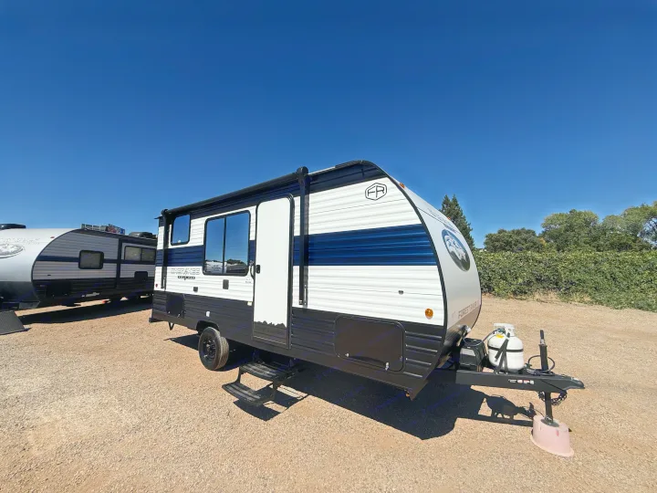 A white, blue, and black Forest River Cherokee Wolf Pup travel trailer RV rental, parked on gravel under a clear sky.. Forest River Cherokee Wolf Pup 2026