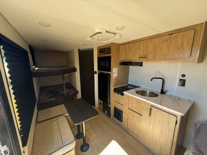 This rv rental interior features a compact kitchenette, bunk beds, and a cozy dinette, ideal for a comfortable road trip.. Forest River Cherokee Wolf Pup 2026
