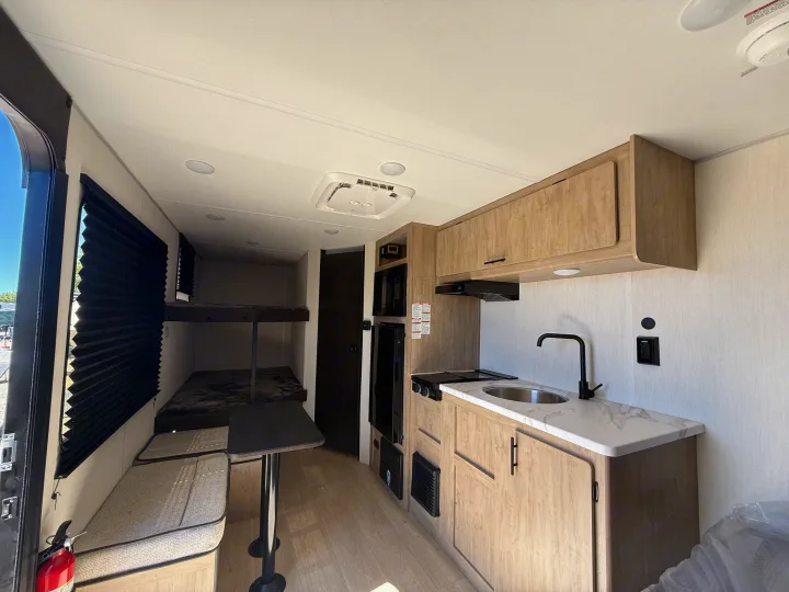 This rv rental shows a bright, modern interior with a well-equipped kitchenette, cozy bunk beds, and a functional dinette area.. Forest River Cherokee Wolf Pup 2026