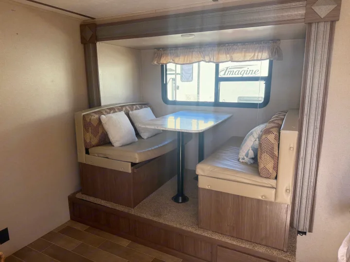 This RV rental features a cozy dinette with booth seating, a table, and a window, ideal for meals in your travel trailer.. Keystone RV Hideout 2020