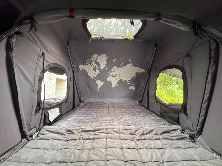 Interior of a cozy, quilted roof-top tent with a world map wall and open windows, ideal for an rv rental adventure.. Jeep Wrangler Rubicon Unlimited 2021