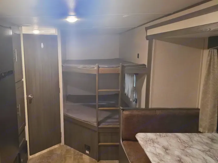 RV rental interior featuring bunk beds, a dinette with a marble-look table, and a compact bathroom/storage area.. Shasta Shasta 2020