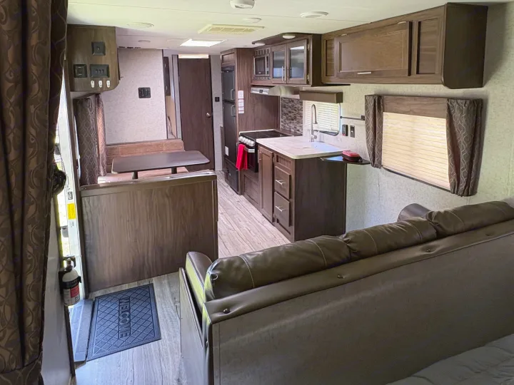 This RV rental offers a well-equipped interior, featuring a kitchen, dinette, sofa, and wood-toned finishes for comfortable travel.. Forest River Cherokee Grey Wolf 2018