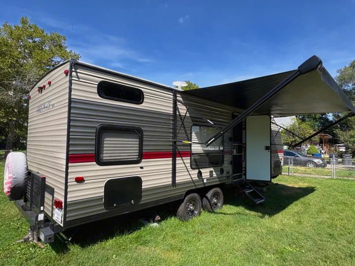 Grey Wolf RV rental with awning extended, parked on grass under a blue sky. Ready for your next camping adventure!. Forest River Cherokee Grey Wolf 2018