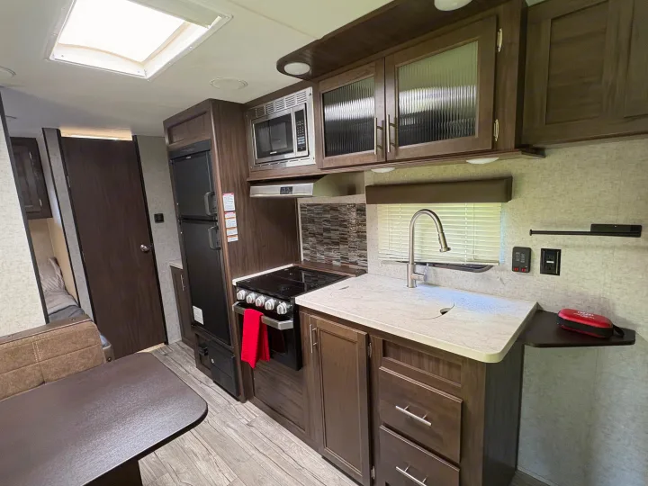 RV rental: full kitchen with microwave, stove, sink, fridge, dark wood cabinetry, and dinette.. Forest River Cherokee Grey Wolf 2018