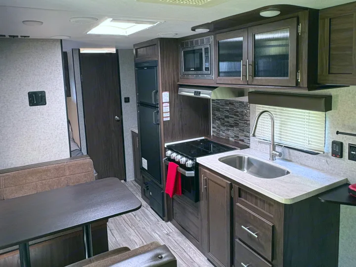 RV rental: Interior shows a modern kitchen with dark cabinetry, stove, microwave, sink, and a comfortable dining area.. Forest River Cherokee Grey Wolf 2018