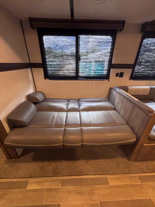 This RV rental features a grey faux leather convertible sofa bed, roller blinds, and mixed flooring for a cozy, functional interior.. Crossroads RV Zinger 2021