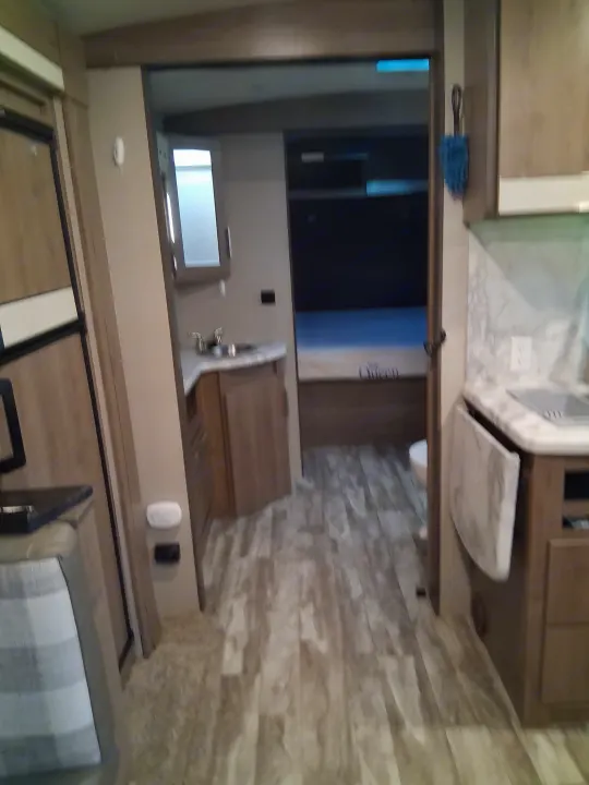 RV rental interior: A cozy hallway connecting a kitchen, small bathroom, and a bedroom with a Queen mattress.. Grand Design Imagine 2021