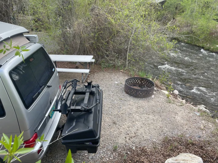 RV rental camper van at a scenic riverside campsite, featuring a picnic table, fire pit, and a cargo rack.. Eurovan Camper Eurovan Camper Class B 2002
