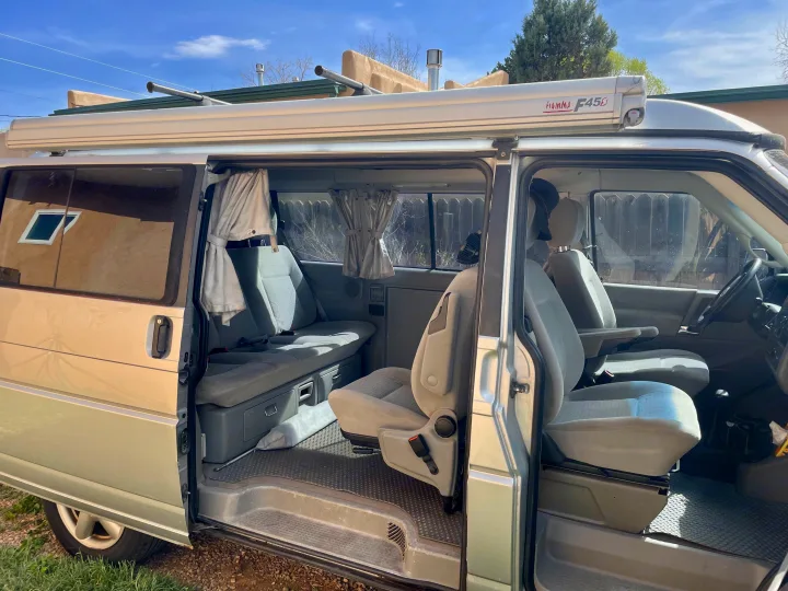 Inside a light camper van, side door open, revealing versatile seating and roof awning. Perfect for an RV rental adventure.. Eurovan Camper Eurovan Camper Class B 2002