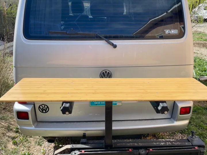 Outdoor dining on the go! This RV rental camper van features a bamboo rear table extended from its tailgate. A silver VW van.. Eurovan Camper Eurovan Camper Class B 2002