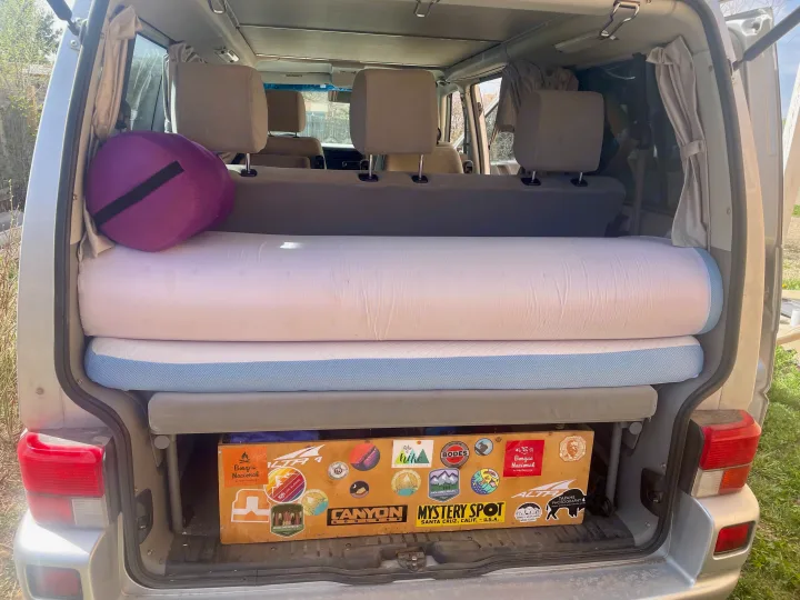 RV rental ready for adventure! Inside this camper van, find rolled mattresses, a pillow, & sticker-covered storage box.. Eurovan Camper Eurovan Camper Class B 2002
