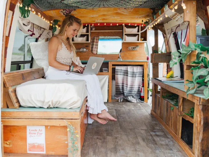 Woman working on a laptop in a cozy, custom-built rv rental interior, ideal for digital nomads.. Chevrolet G20 Chevy Van 1990