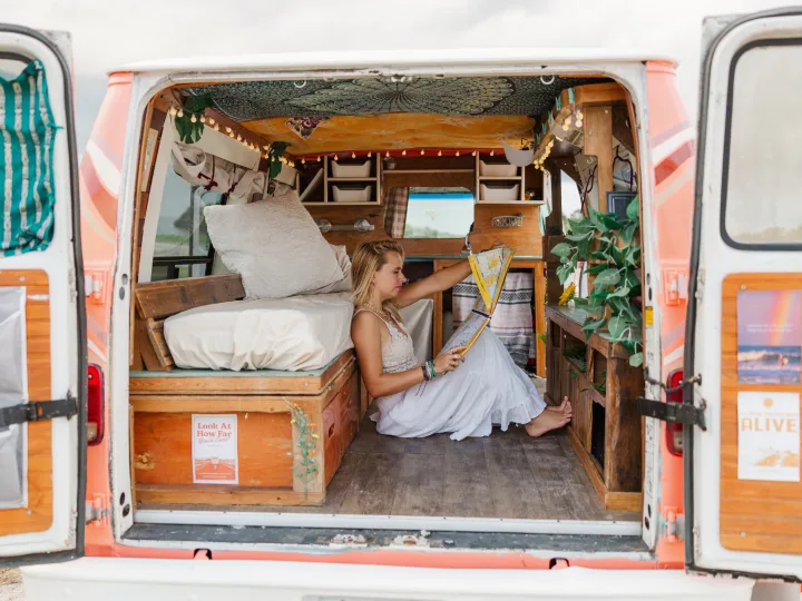 Cozy RV rental adventure: Woman studies a map inside a beautifully converted camper van, perfect for road trip travel.. Chevrolet G20 Chevy Van 1990