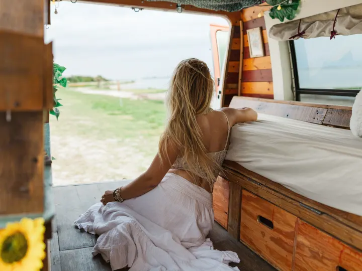 Woman enjoying the peaceful outdoor view from her cozy **RV rental** **camper van**. Perfect for embracing **van life** and **travel**.. Chevrolet G20 Chevy Van 1990