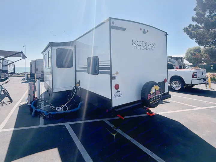 RV rental Kodiak travel trailer parked at a coastal campground with hookups and ocean views on a sunny day.. Dutchmen Kodiak 2026
