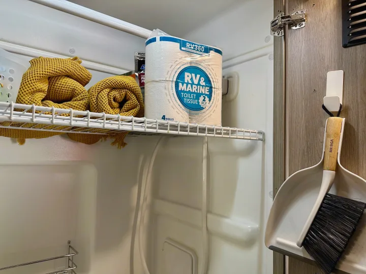 RV rental storage: RV-specific toilet paper, yellow towels, and a MR. SIGA dustpan/brush neatly stored.. Winnebago Solis 2023